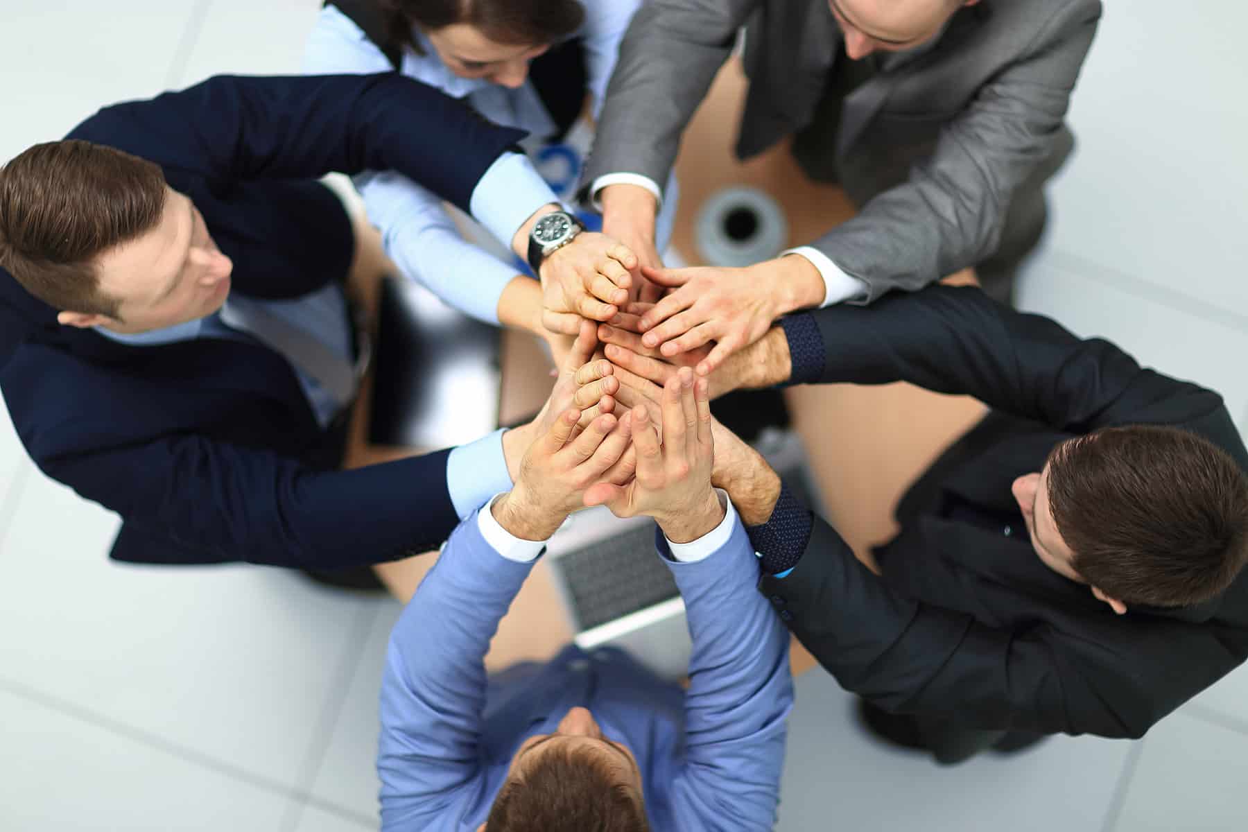 success and winning concept - happy business team giving high five in office. top view